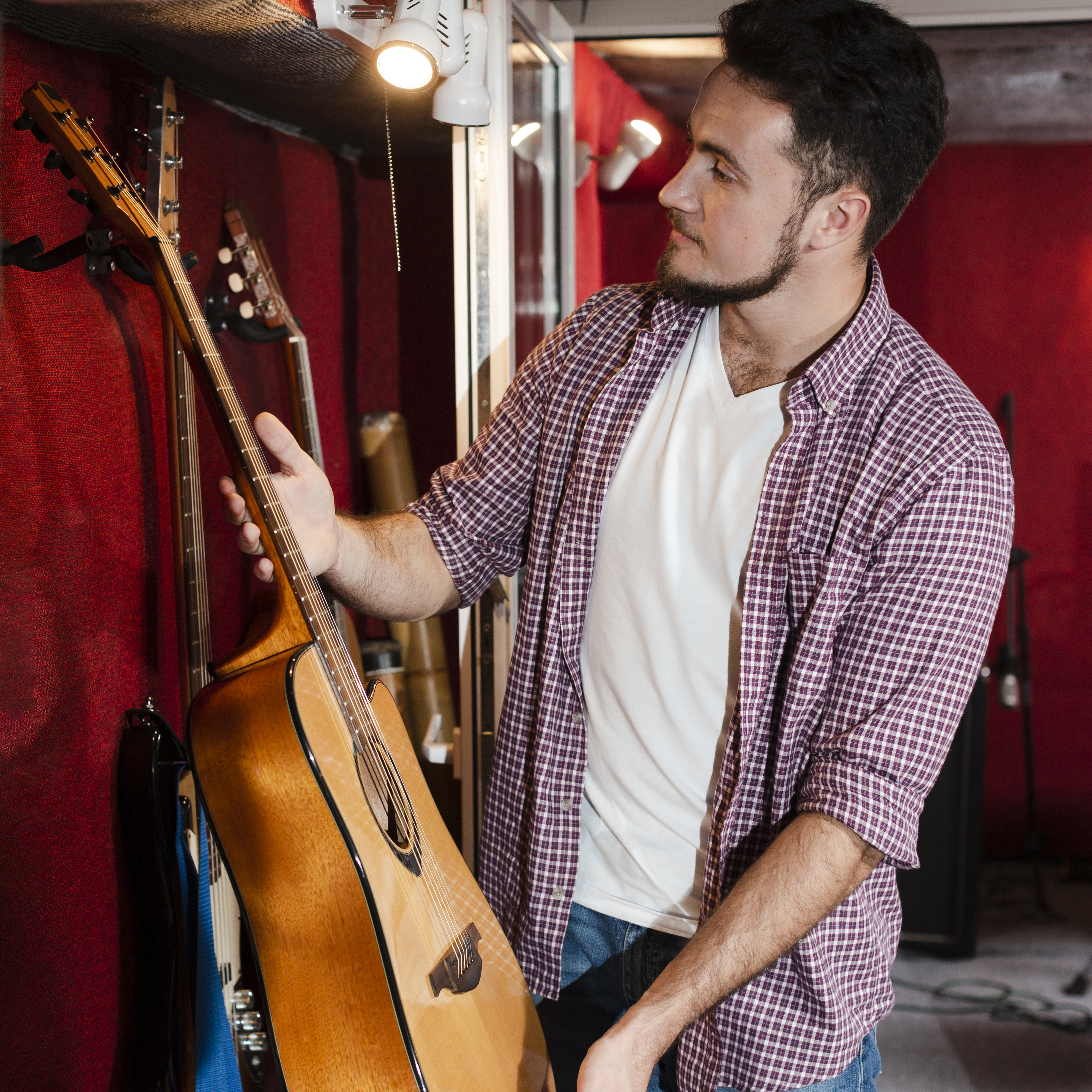 man choosing guitar from stack studio